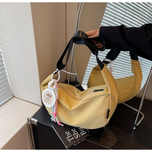 Close-up of yellow nylon hobo bag with black strap and cute Capybara charm detail