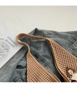 Detail of knit shoulder bag featuring hollow mesh texture and a cute patch applique