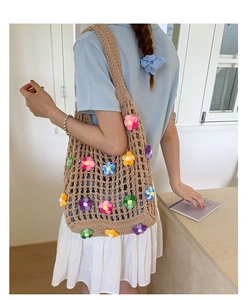 Detail of handmade khaki crochet mesh bag with colorful 3D flower accents and wide strap