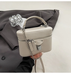 Detail view of cream mini vanity case bag featuring grainy leather texture and silver chain strap