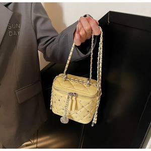 Dettaglio di una borsa box gialla trapuntata con catena argento e ciondolo camelia