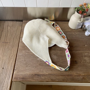 Détail du sac cabas au crochet beige avec broderies florales colorées sur la bandoulière
