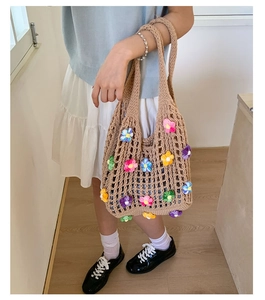 Detail of handmade crochet tote bag with colorful 3D floral accents on khaki mesh