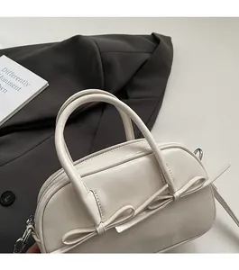 Détail du sac Boston blanc avec nœud décoratif et fermeture éclair en métal argenté