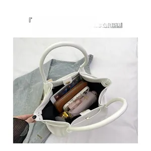 Top view showing the spacious interior of a white tote bag with wallet, phone, and tablet