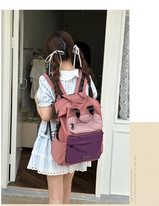 Side view of a pink and purple color-block canvas backpack worn by a model in daylight