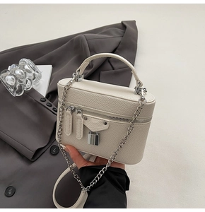Detailed view of white box handbag with lychee texture, silver rivets, and mini padlock