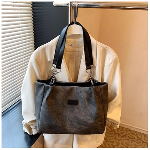 Detail of dark grey tote bag featuring black leather handles and silver metal hardware