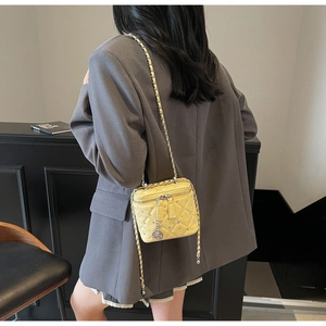 Dettaglio della mini borsa gialla trapuntata con cristalli e ciondolo a camelia