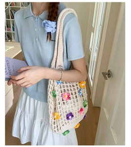 Detailed close-up of a white knit tote bag with colorful 3D crochet floral embellishments
