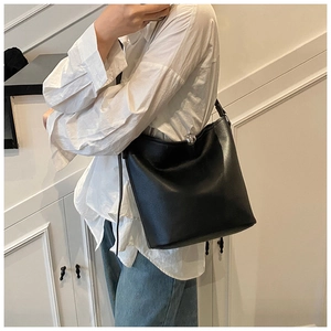 Détail du sac seau noir en cuir grainé avec fermoir sphérique argenté et bandoulière