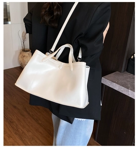 White large capacity tote bag shown on shoulder with side accordion fold structure