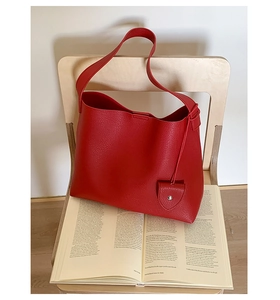 Dettaglio della borsa tote in pelle rossa martellata con ciondolo coordinato