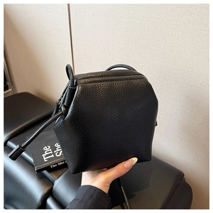 Détail du sac bandoulière noir avec texture grainée et design géométrique unique