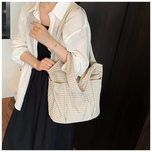 Detail of checkered canvas tote bag with functional side pockets shown on a model