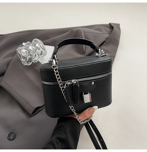Detailed close-up of black pebble leather crossbody bag with silver hardware and chain strap
