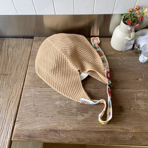 Détail de la bandoulière en crochet fleuri rétro sur un sac fourre-tout beige ajouré