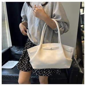 Minimalist white leather tote bag with drawstring detail shown on shoulder in home setting