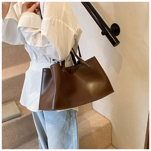 Detail of a large dark brown tote bag with smooth finish and adjustable shoulder strap