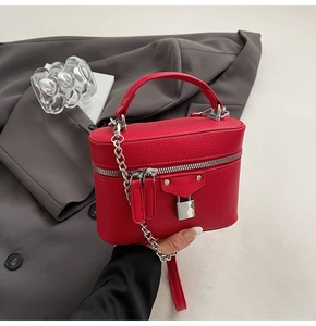 Close-up of a red textured leather box bag with silver hardware and chain strap