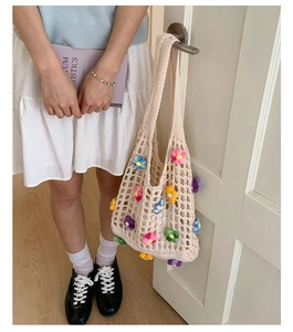 Detailed close-up of handmade crochet hollow tote bag with 3D colorful knit flowers