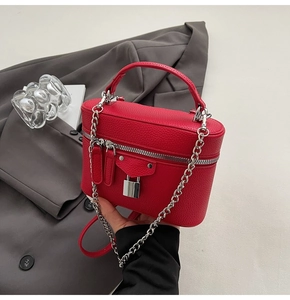 Detail of red pebbled leather mini box bag with silver hardware and chain strap