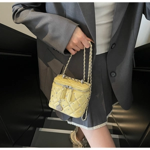 Dettaglio mini borsa gialla trapuntata con strass e ciondolo floreale in argento su zip