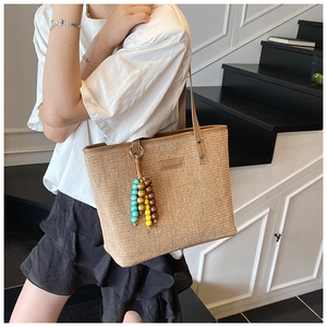 Straw beach tote with brown leather handles and colorful beaded tassel detail