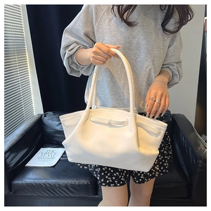 Detail of a minimalist cream shoulder bag featuring elegant ruched leather and thin handles