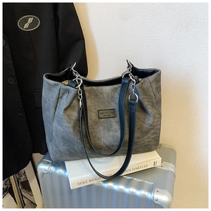 Close-up of deep gray tote bag with leather straps, chain detail and fashion label