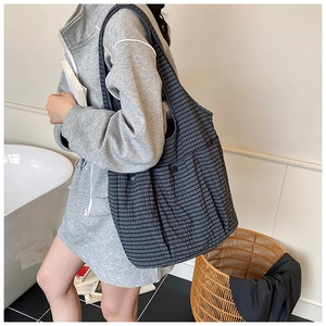Detail of grey plaid canvas tote bag with snap-button pocket in a minimal home setting