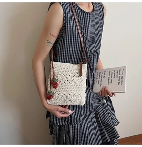 Detail of hand-crocheted beige shoulder bag with strawberry charms and brown leather strap