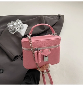 Detailed shot of a pink pebbled leather mini crossbody bag with silver chain and lock