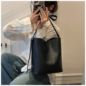 Détail du sac seau en cuir grainé noir avec fermoir boule en métal argenté brillant