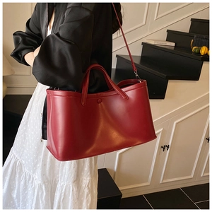 Detailed view of deep red matte leather tote bag worn as a shoulder bag on a model