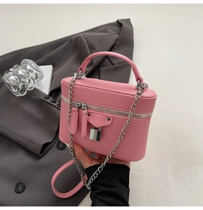 Detailed macro shot of pink litchi grain leather texture and silver padlock on vanity bag