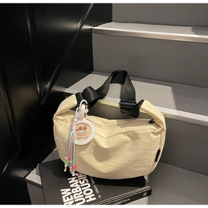 Detail of beige nylon crescent bag with Capybara charm and adjustable black strap