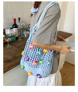 Detail of hand-woven light blue knit shoulder bag with 3D colorful crochet flowers