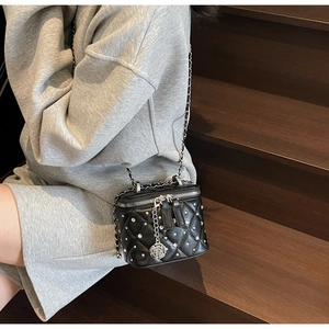 Dettaglio della mini borsa a scatola trapuntata nera con strass e ciondoli a camelia
