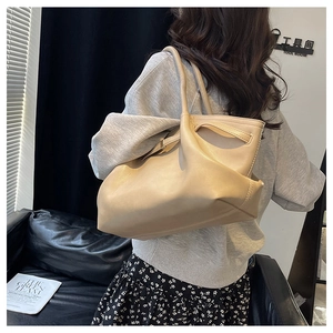 Detail of a beige soft leather tote bag with elegant draped texture and slim shoulder straps
