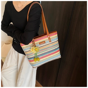 Detail of colorful striped woven tote bag with brown leather handles and sunflower charm