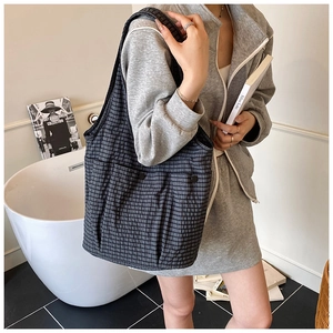 Close-up of dark grey plaid tote bag featuring side pockets and textured fabric material