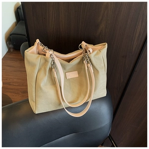 Detail of sage green canvas tote with pink handles and metal chain rings on a leather seat