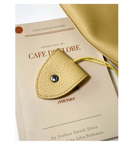 Dettaglio di un accessorio in pelle gialla con anello d'argento su un libro vintage