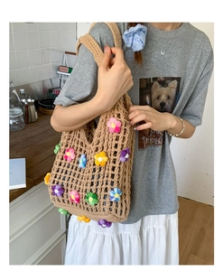 Detail of crochet tote bag featuring colorful 3D floral accents and woven texture