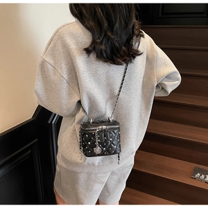 Dettaglio di una mini borsa trapuntata nera con perle argentate e decorazione a catena