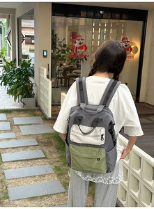 Detail of color-block canvas backpack showing multi-pocket design and ergonomic shoulder straps