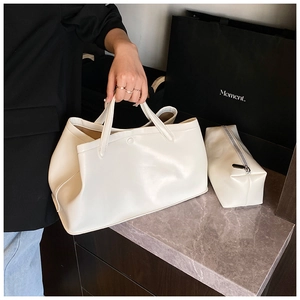 Close-up of white minimalist leather tote bag and zipper pouch set on marble surface