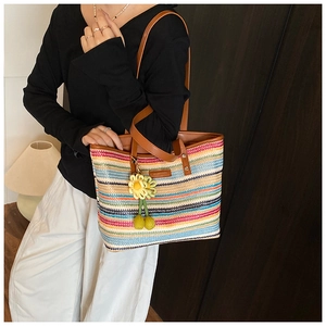 Detail of colorful striped woven tote bag with sunflower charm and leather shoulder strap