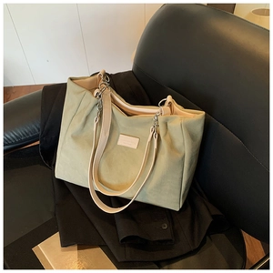 Detail of light green tote bag with cream straps and silver chain hardware on leather